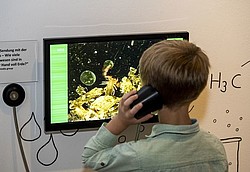 Kind mit Kopfhörer in der Ausstellung 2Expedition Erde"