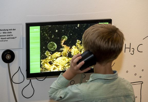 Kind mit Kopfhörer in der Ausstellung 2Expedition Erde"