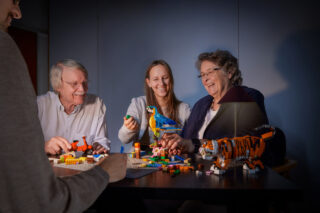 Vier Personen bauen mit LEGO Steinen und Modellen