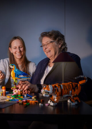 Vier Personen bauen mit LEGO Steinen und Modellen