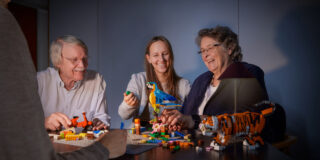 Vier Personen bauen mit LEGO Steinen und Modellen