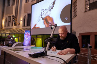 Nic Klein beim Zeichnen der Marvel-Figur Thor während eines Live-Talks im Rahmen der Sonderausstellung "Superheroes".