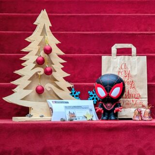 Weihnachtspaket: Spardose "Spider-Man", Generationenkarte für die Sonderausstellung "Superheroes", Geschenktüte und weihnachtliche Dekoration.
