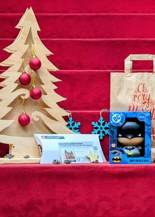 Weihnachtspaket: Spardose "Batman", Generationenkarte für die Sonderausstellung "Superheroes", Geschenktüte und weihnachtliche Dekoration.
