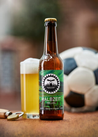 Fotografie des Bieres "Halbzeit-Helles" mit Bierglas, Fußball und Kronkorken.